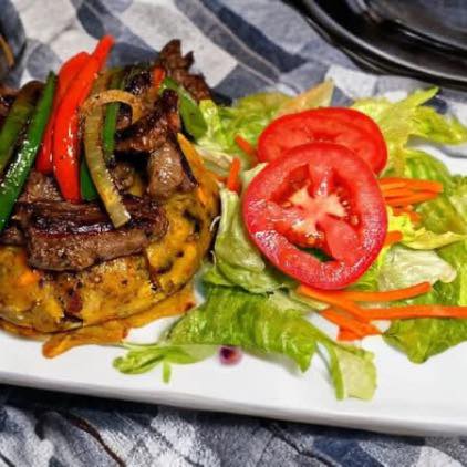 Bistec con mofongo topped with sauteed peppers and onions, served with a fresh salad at La Garita Restaurant
